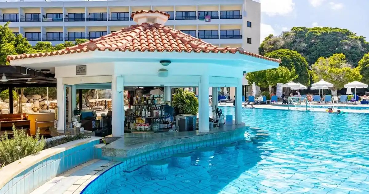 A large outdoor lagoon swimming pool, and shaded swim-up bar at the Avanti Hotel in Kato, Paphos, Cyprus.