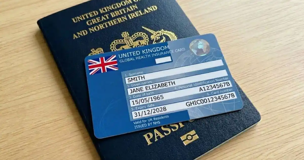 A picture of the GHIC card placed over a British Passport, sitting on top of a wooden table.